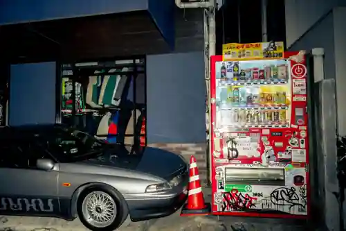 Sticker-covered Coca-Cola vending machine beside a car